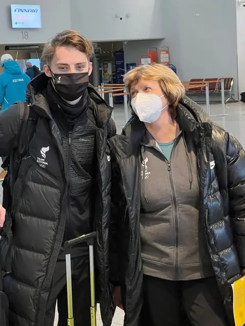 Uisutaja ja treener Team Estonia riietes lennujaamas olümpiale sõitmas