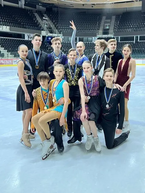Noored uisutajad medalite ja võistluskostüümidega ühispildil jääl