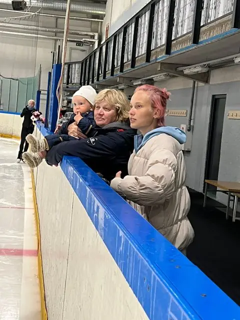 Naised väikelapsega jälgivad uisutreeningut jäähalli poordi ääres