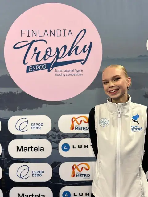 Naeratav uisutaja Team Estonia vestis Finlandia Trophy bänneri ees