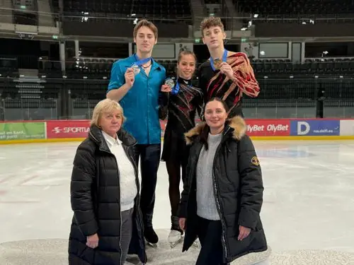 Kolm medalitega uisutajat koos treeneritega jäähallis pärast võistlust
