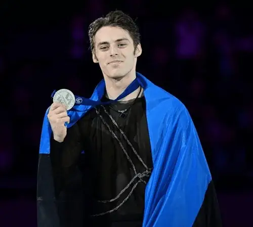 Meesuisutaja Eesti lipuga õlgadel näitab medalit autasustamisel