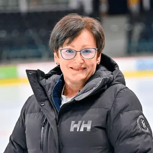 Naine lühikeste juustega ja prillidega, kannab musta jakki valge logoga